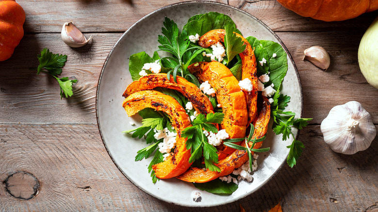Slices of skin-on roasted pumpkin on salad leaves with feta