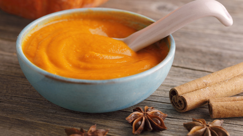Bowl of pumpkin surrounded by spices