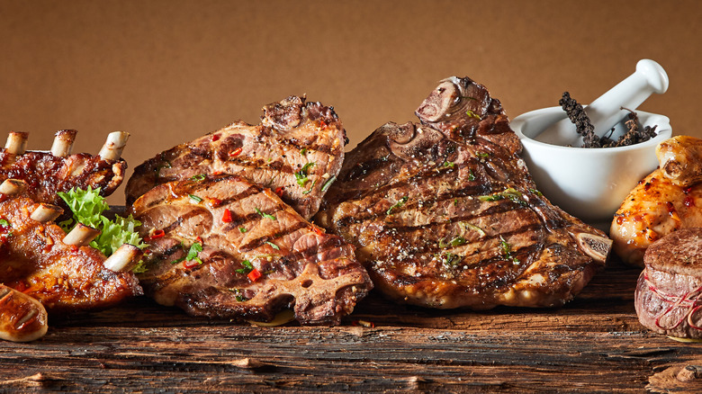 grilled pork chops, sausages, and ribs on wooden surface