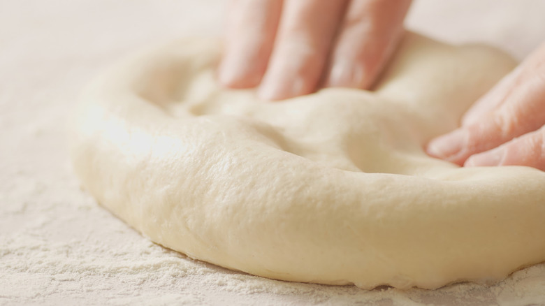 Hands shaping ball of pizza dough