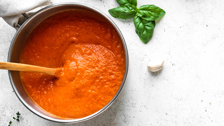 Homemade pizza sauce on counter surrounded by ingredients
