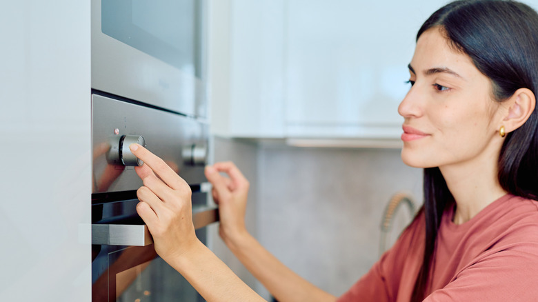 Woman adjusting oven temperature