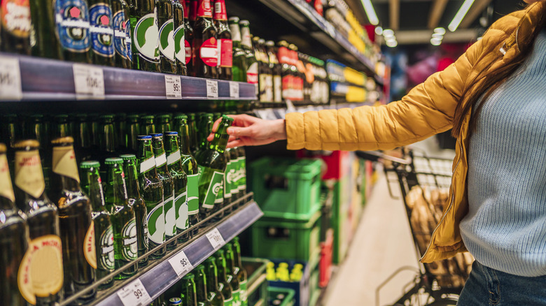 Customer picking up beer at grocery store