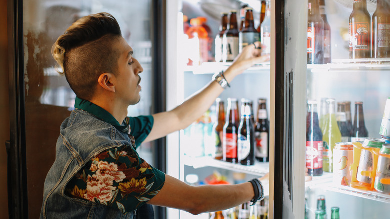 Person choosing bottle of beer from chiller
