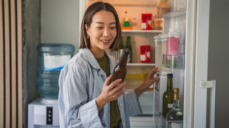 Woman picking beer from kitchen fridge