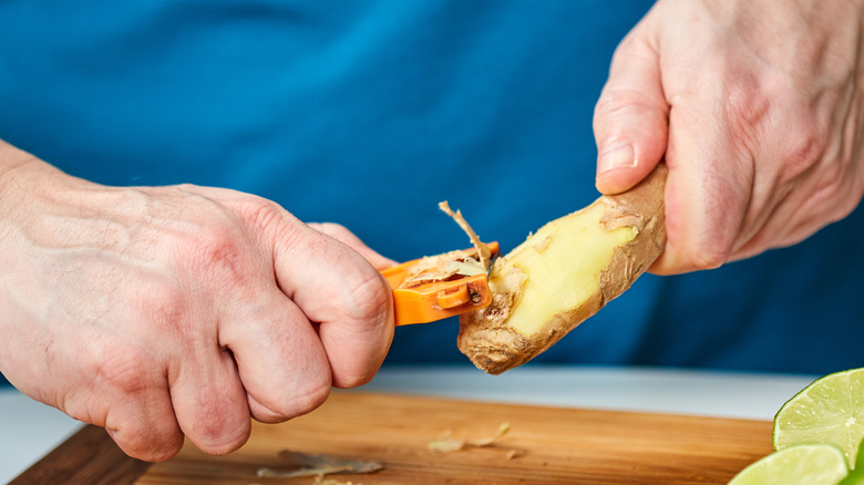 man's hands peeling ginger
