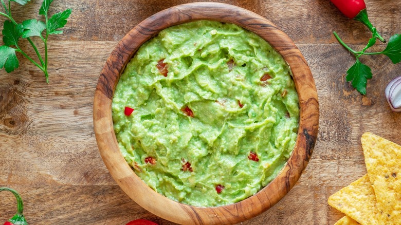 bowl of green guacamole with red pepper bits