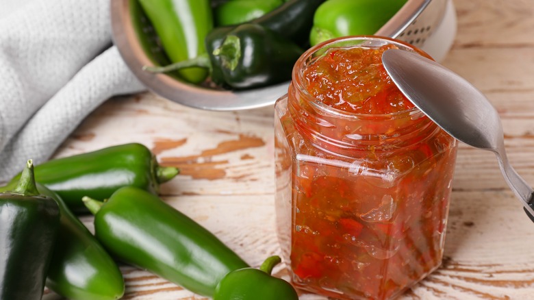 jar of pepper jam next to bowl of jalapeños