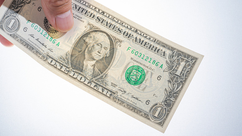 Hand holding $1 dollar bill