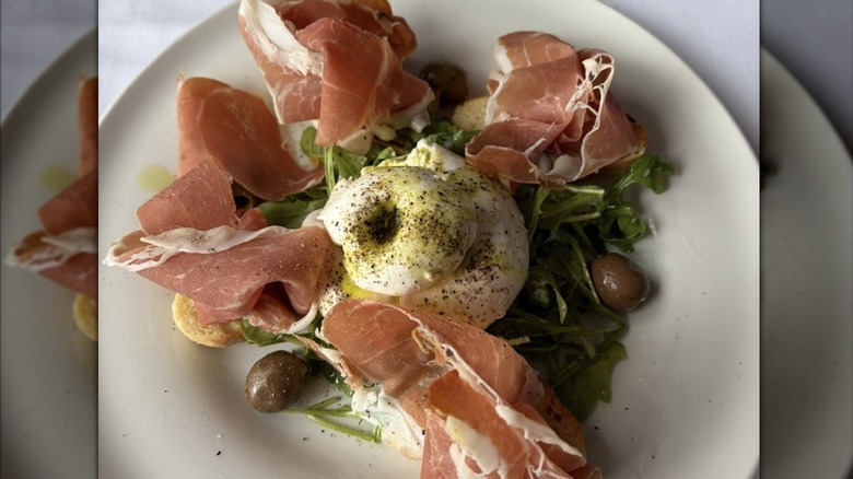 A dinner plate with prosciutto, olives, and greens from Il Fornaio