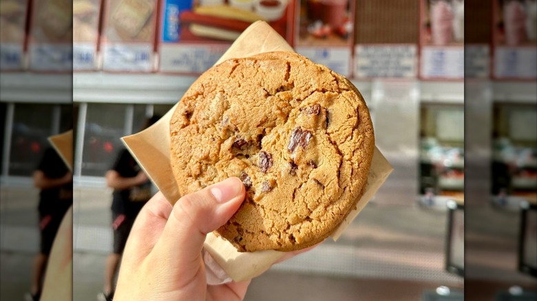 Hand holding chocolate chip cookie from Costco food court.