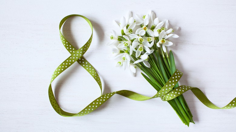 Green polka dot ribbon in the shape of an 8 around white flowers