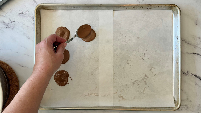 Hand spooning chocolate rounds onto baking sheet