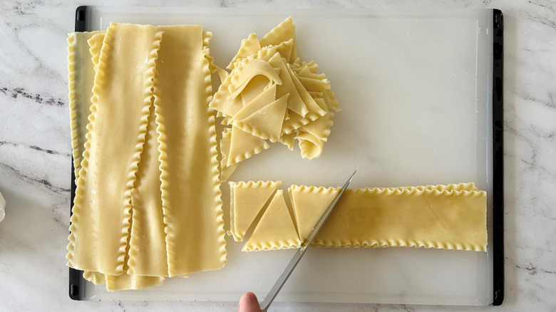 Knife cutting strips of lasagna noodles into triangles