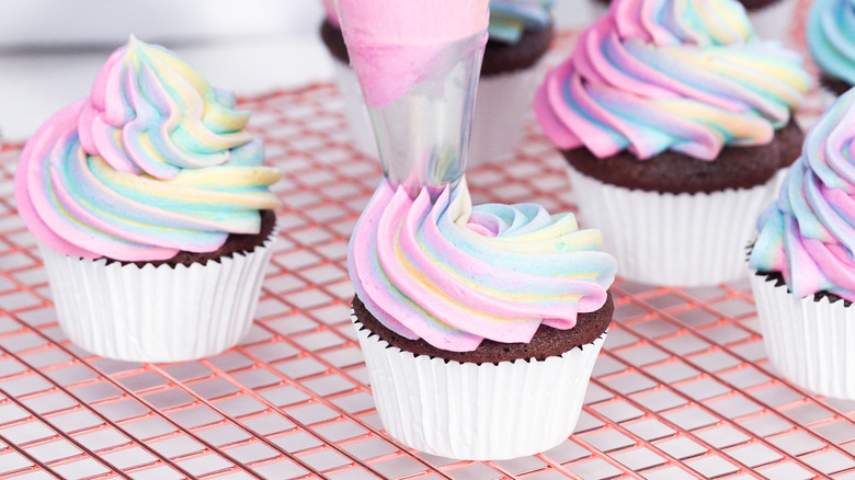 Piping multicolored frosting onto cupcakes