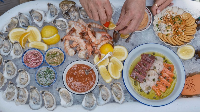 Oysters and various seafood dishes laid out over tub of ice.