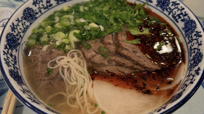 Lanzhou beef soup garnished with chili oil and spring onions