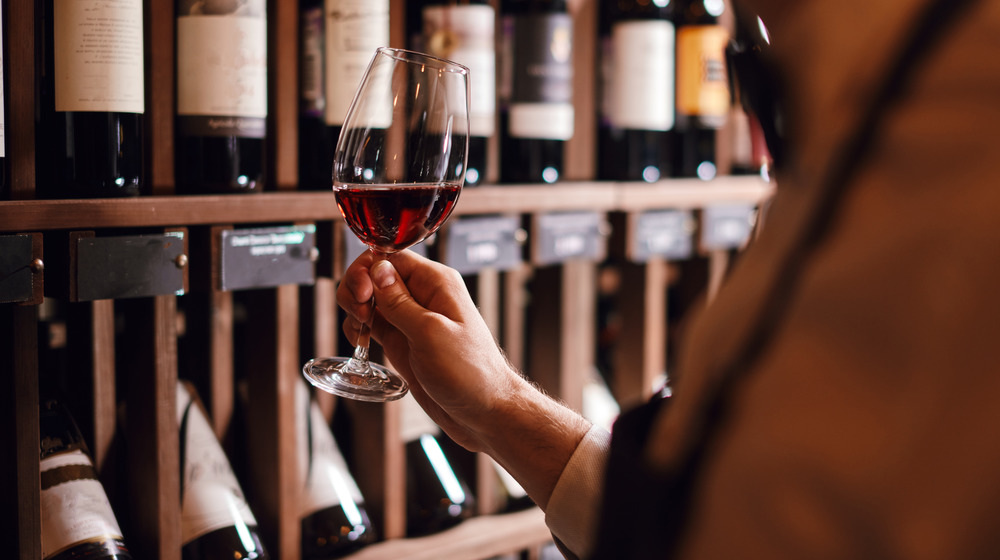 Person holding wine glass in wine cellar