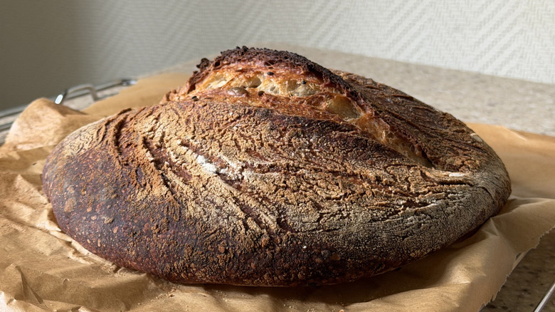 Dark, crusty sourdough bread loaf on parchment paper