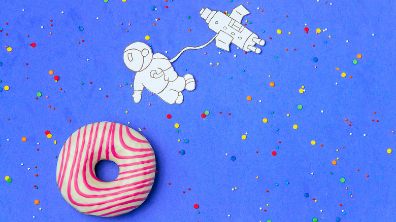 Cartoon astronaut approaching frosted donut