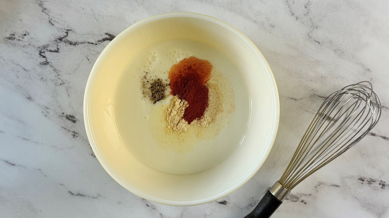 Buttermilk and seasonings in bowl next to whisk