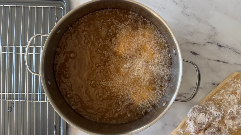 Chicken frying in pot of oil