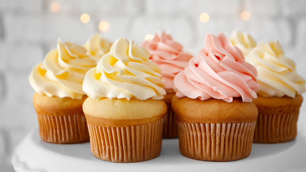 cupcakes on a stand with white and pink frosting