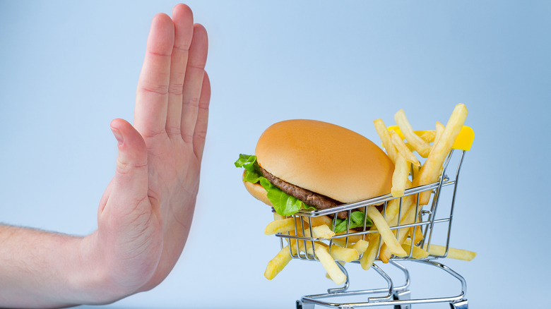 Burger and fries in shopping cart being pushed away by hand