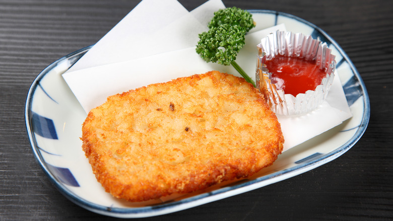 A hash brown patty on a plate with ketchup