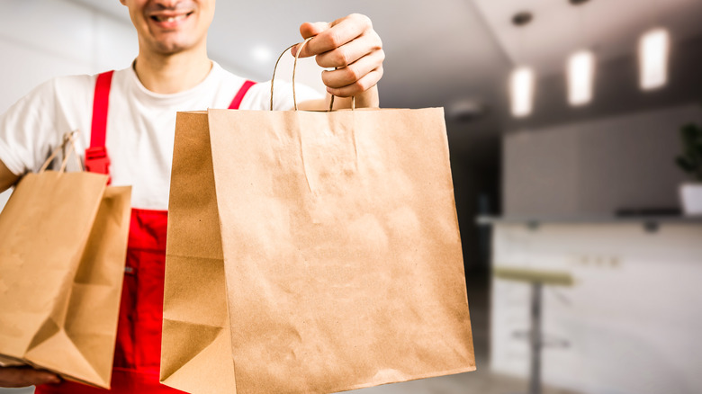 fast food worker holding bags out to customer