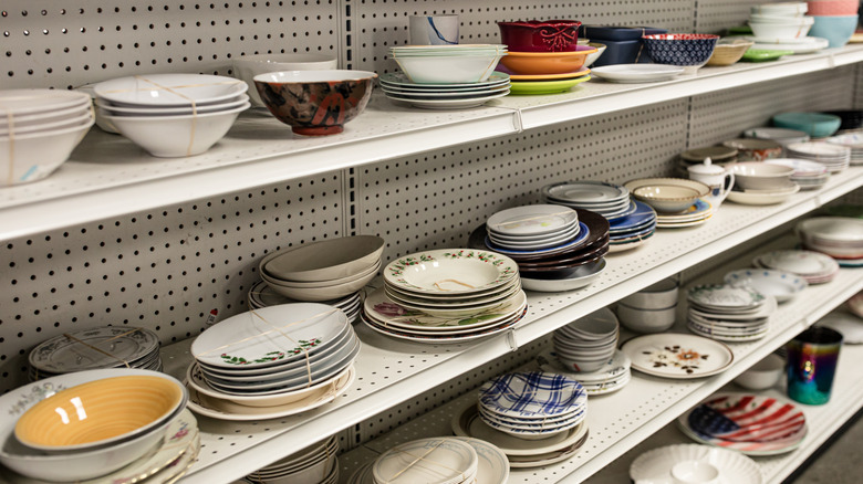 Stacks of bowls and plates on thrift store shelves.