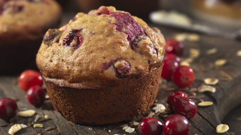 A cranberry muffin with cranberries around it.