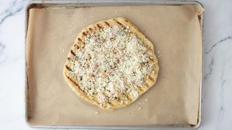 Unbaked white clam pizza on baking sheet