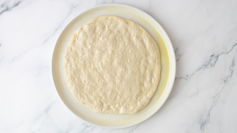 Stretched out pizza dough on plate