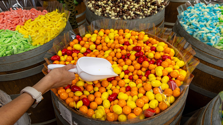 Person scooping candy from barrel