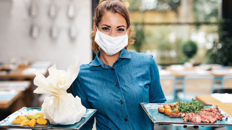 Masked server with plates of food