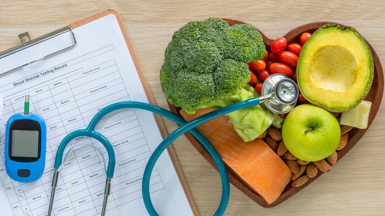 A stethoscope on top of a bowl of veggies, nuts and fruits