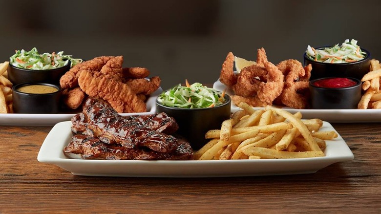 applebee's ribs, wings and chicken strips with fries and salads on plates