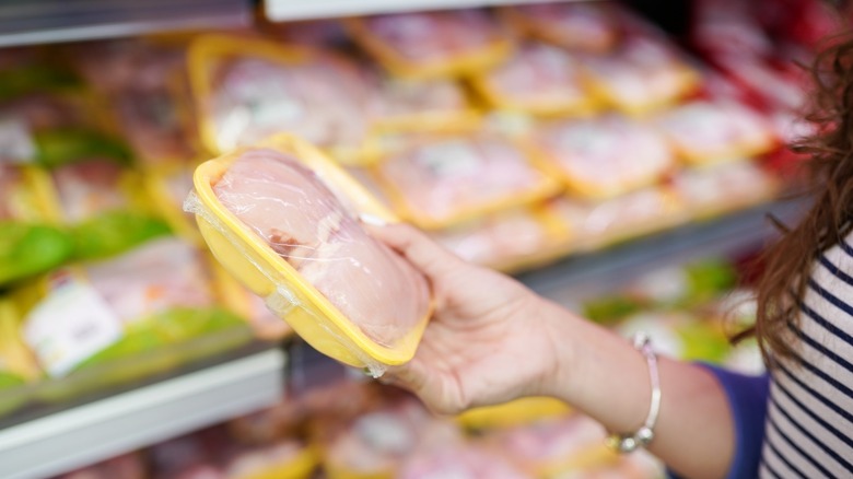 shopper holding raw chicken package