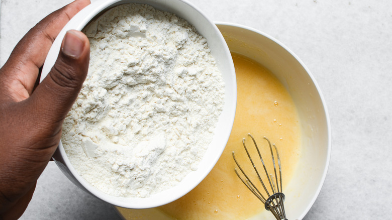 Overhead shot of flour being added to cake batter.