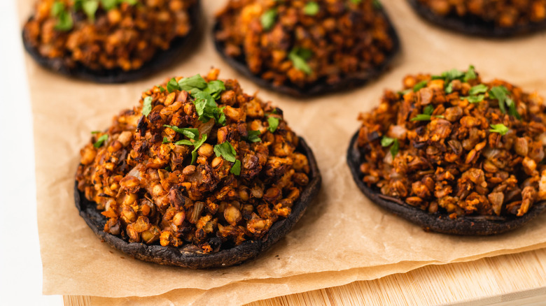 Stuffed portobello mushrooms on parchment-lined wooden board