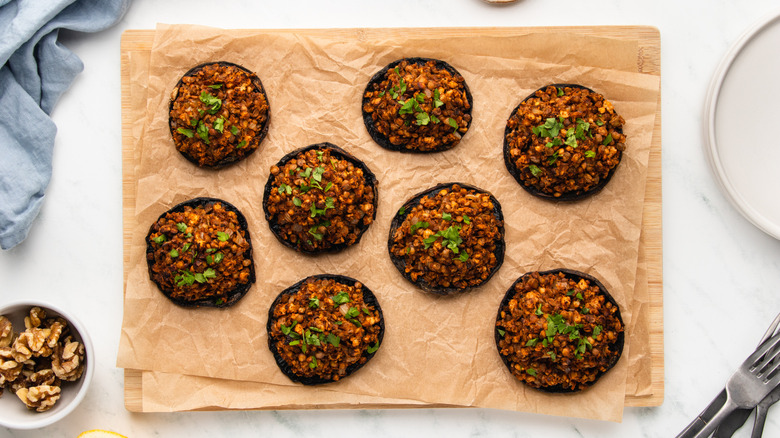 Stuffed portobello mushrooms on parchment-lined wooden board