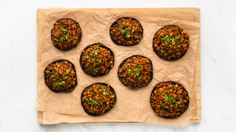 Stuffed portobello mushrooms on parchment-lined wooden board