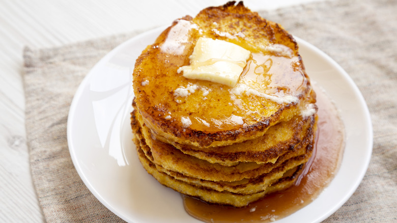close up of johnnycakes on plate with butter and syrup