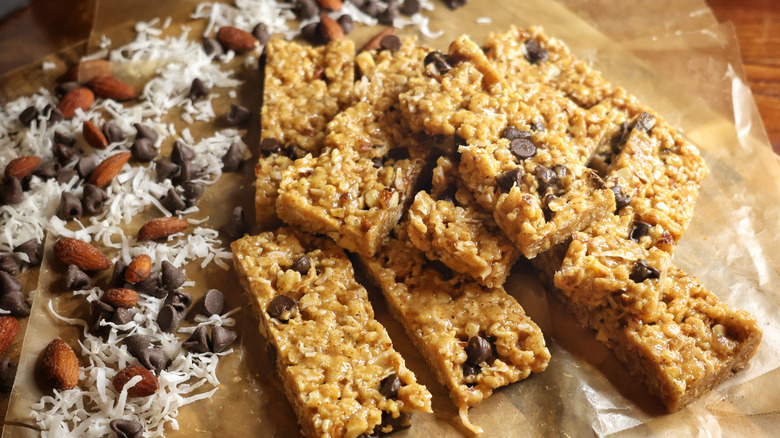 cereal bars on wax paper next to coconut, chocolate chips, and almonds