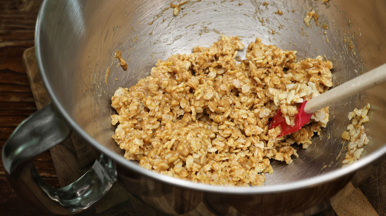 Mixing bowl full of puffed rice cereal mixed with almond butter and honey