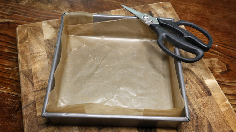 scissors and a baking pan lined with wax paper on a cutting board