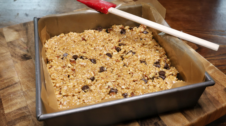 a pan of no-bake cereal bars on a cutting board with a sililone spatula