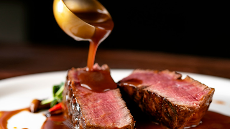 ladle pouring sauce over steak