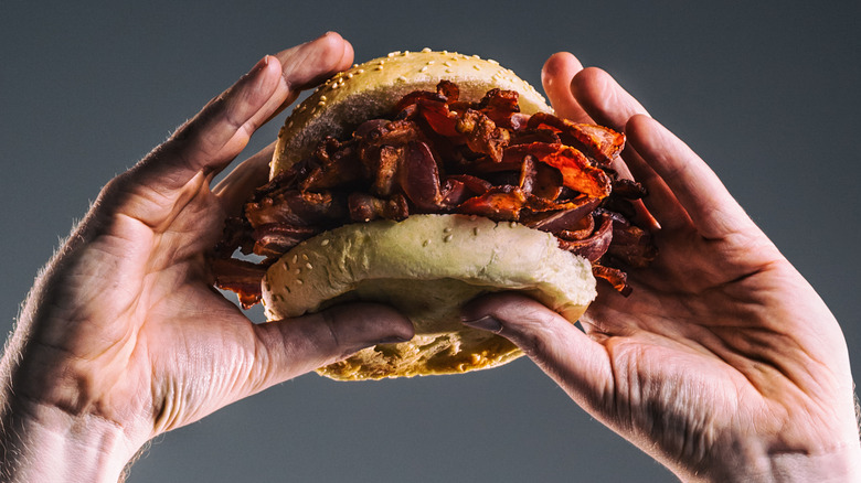 hands holding bacon sandwich